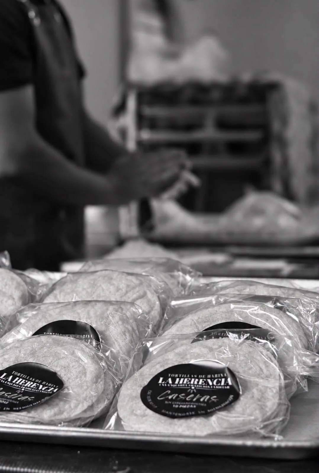 Paquetes de tortillas La Herencia sobre una charola en el área de elaboración